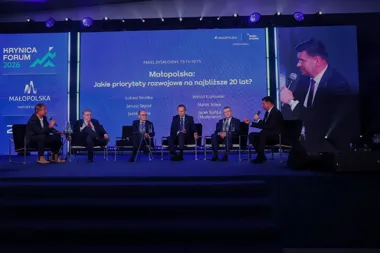 Panel dyskusyjny podczas Krynica Forum 2026, podczas którego sześciu mężczyzn w garniturach siedzi na scenie i rozmawia o priorytetach rozwojowych Małopolski na