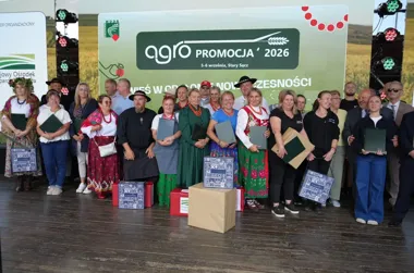 Grupa osób pozuje do pamiątkowego zdjęcia na scenie podczas wydarzenia Agro Promocja 2026 w Starym Sączu, trzymając dyplomy i nagrody.